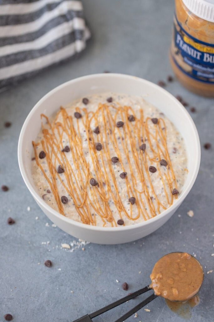 peanut butter overnight oats with chocolate chips and peanut butter drizzle on top with peanut butter on the side