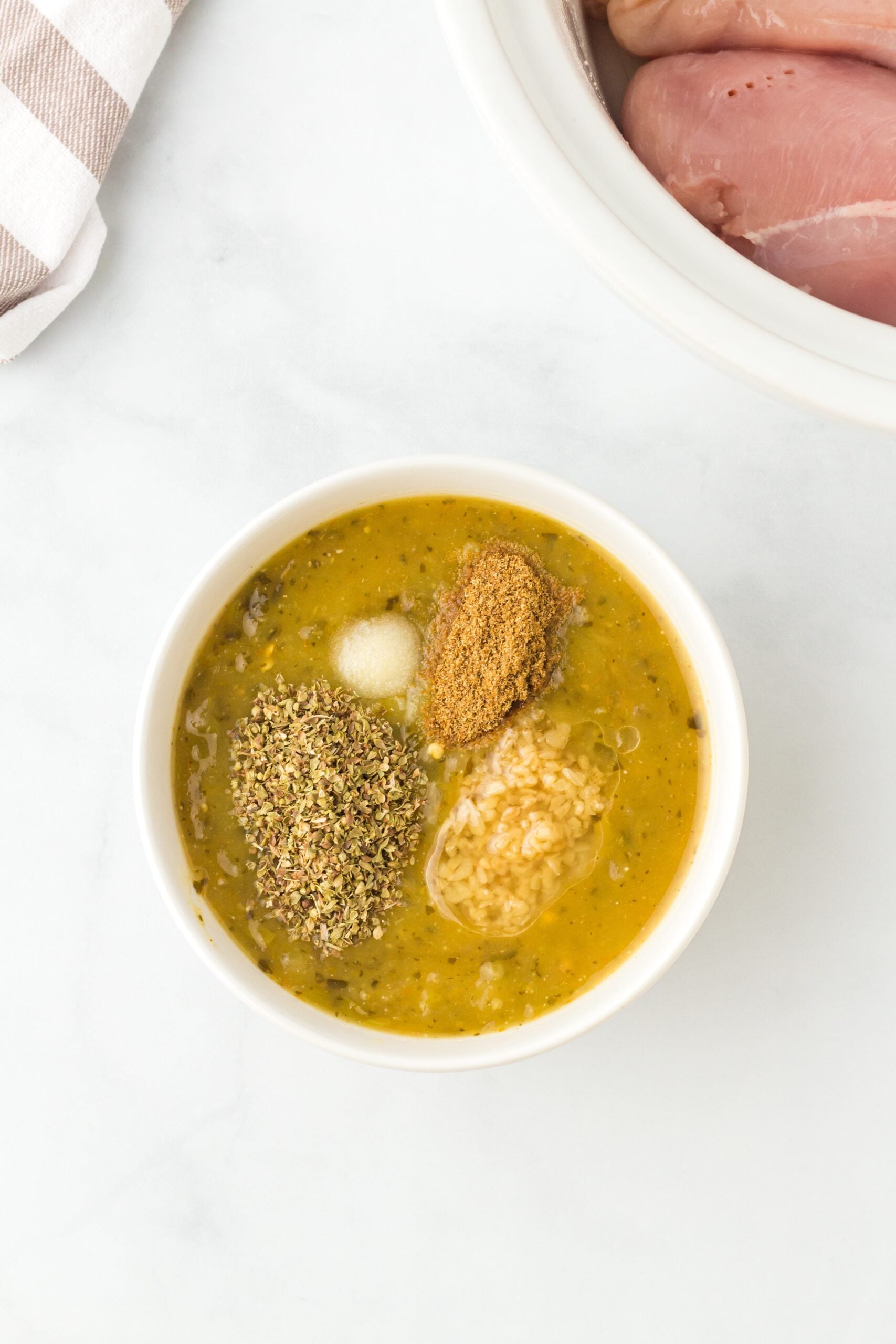 salsa verde, minced garlic, dried oregano, ground cumin and salt in a white bowl before being combined.
