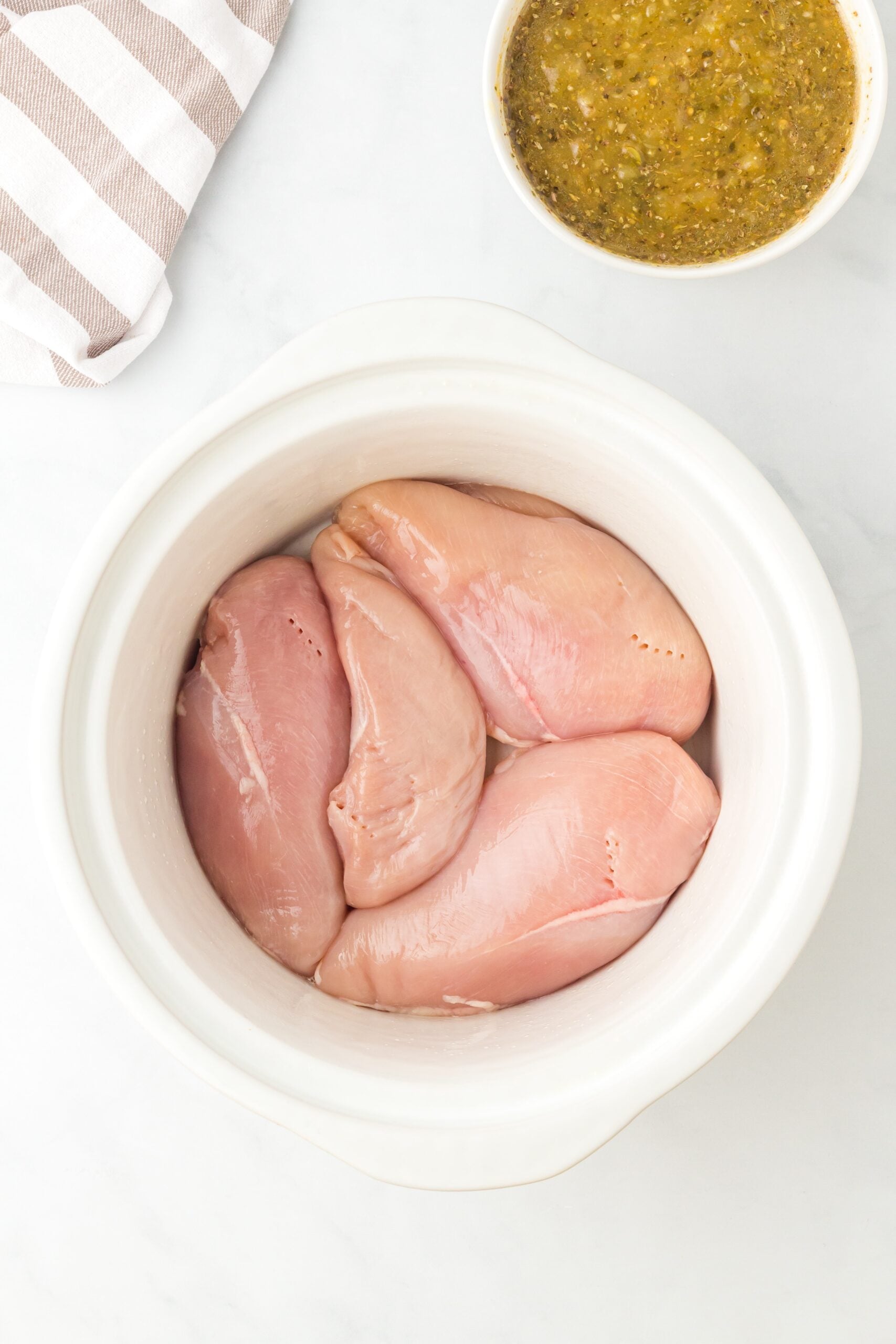 raw chicken breast in a crockpot, viewed from above.