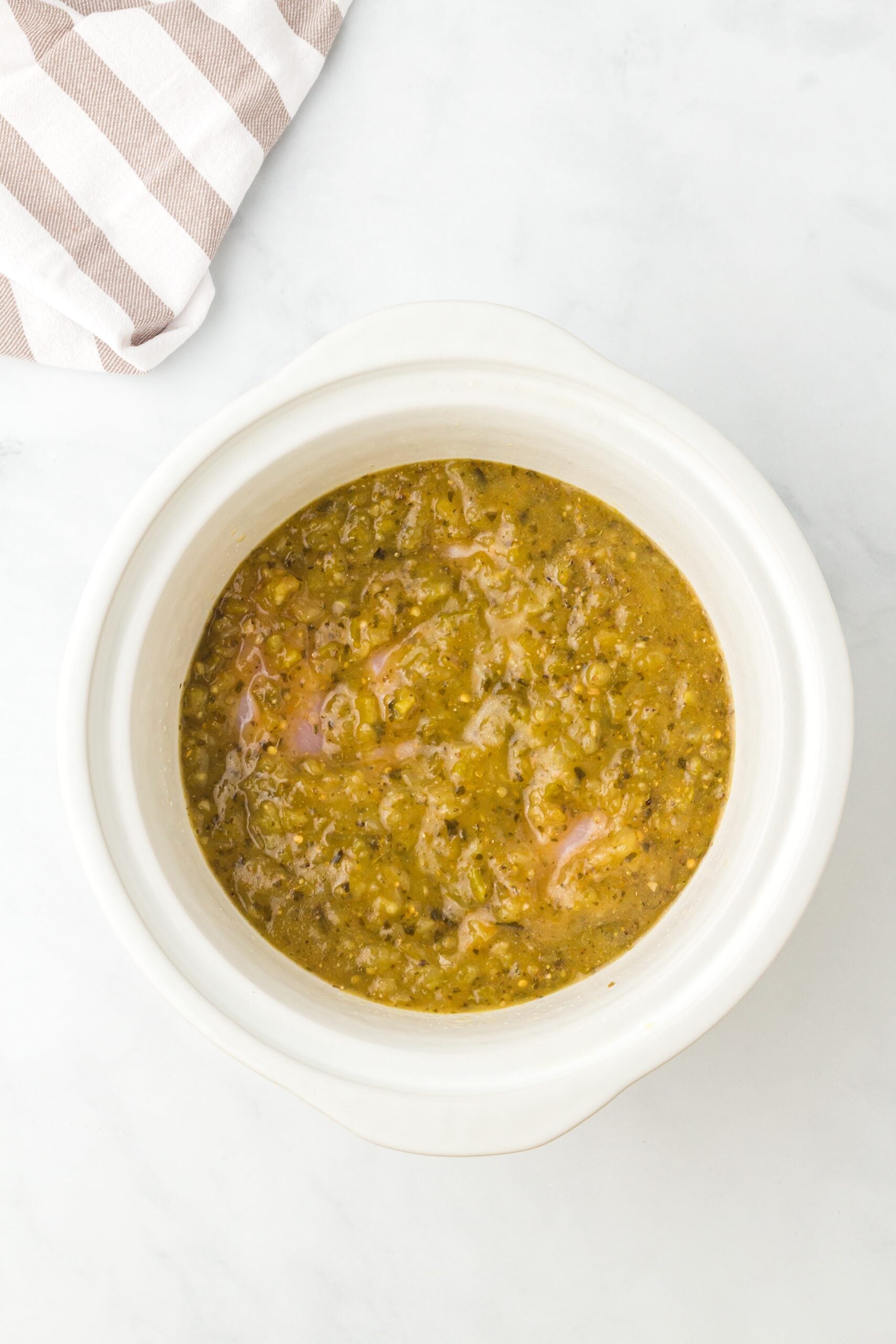 Green salsa in a crockpot, viewed from overhead.