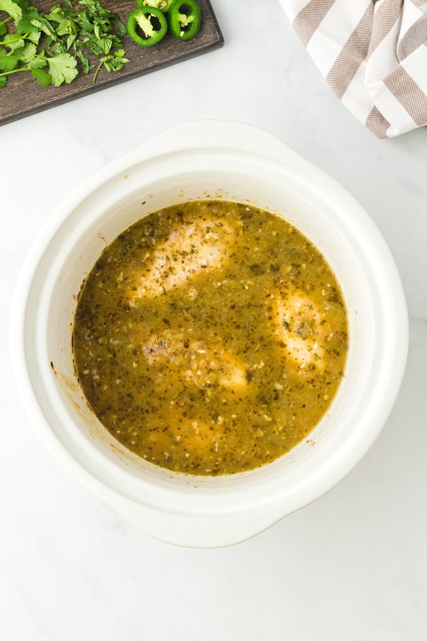 Salsa chicken verde in a white crock pot, viewed from overhead.