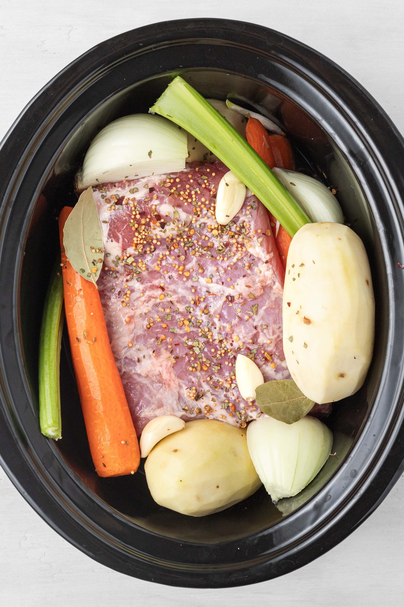 all ingredients for corned beef in a slow cooker, uncooked