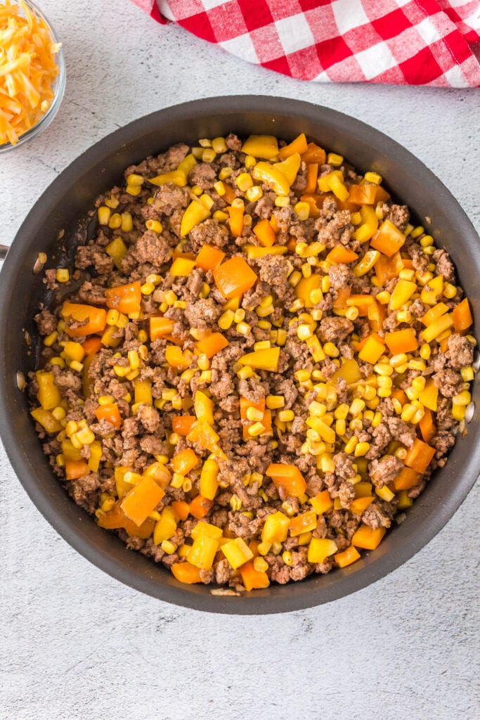 Ground beef, peppers, corn, onion and Mexican spices cooking in a skillet.