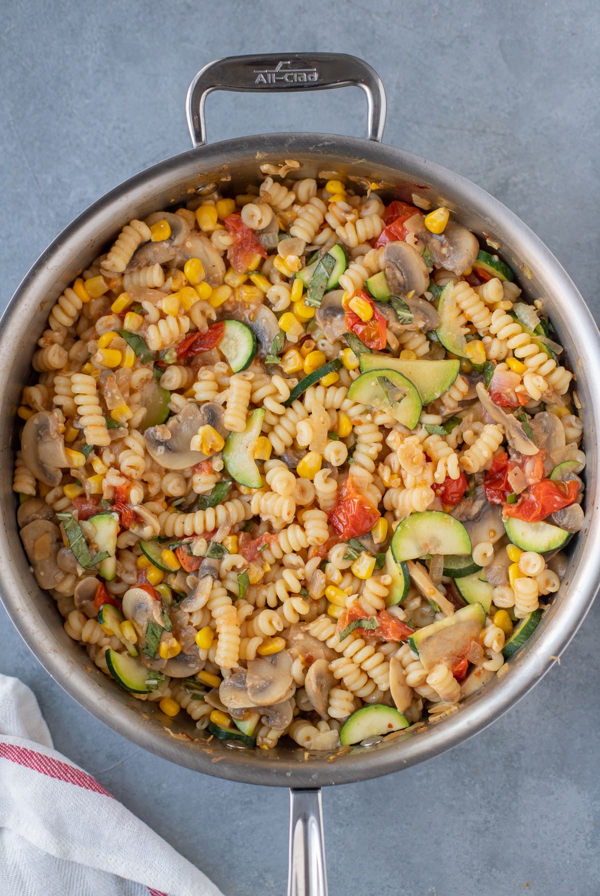 an overhead shot of vegetable pasta in a pan on a grey background
