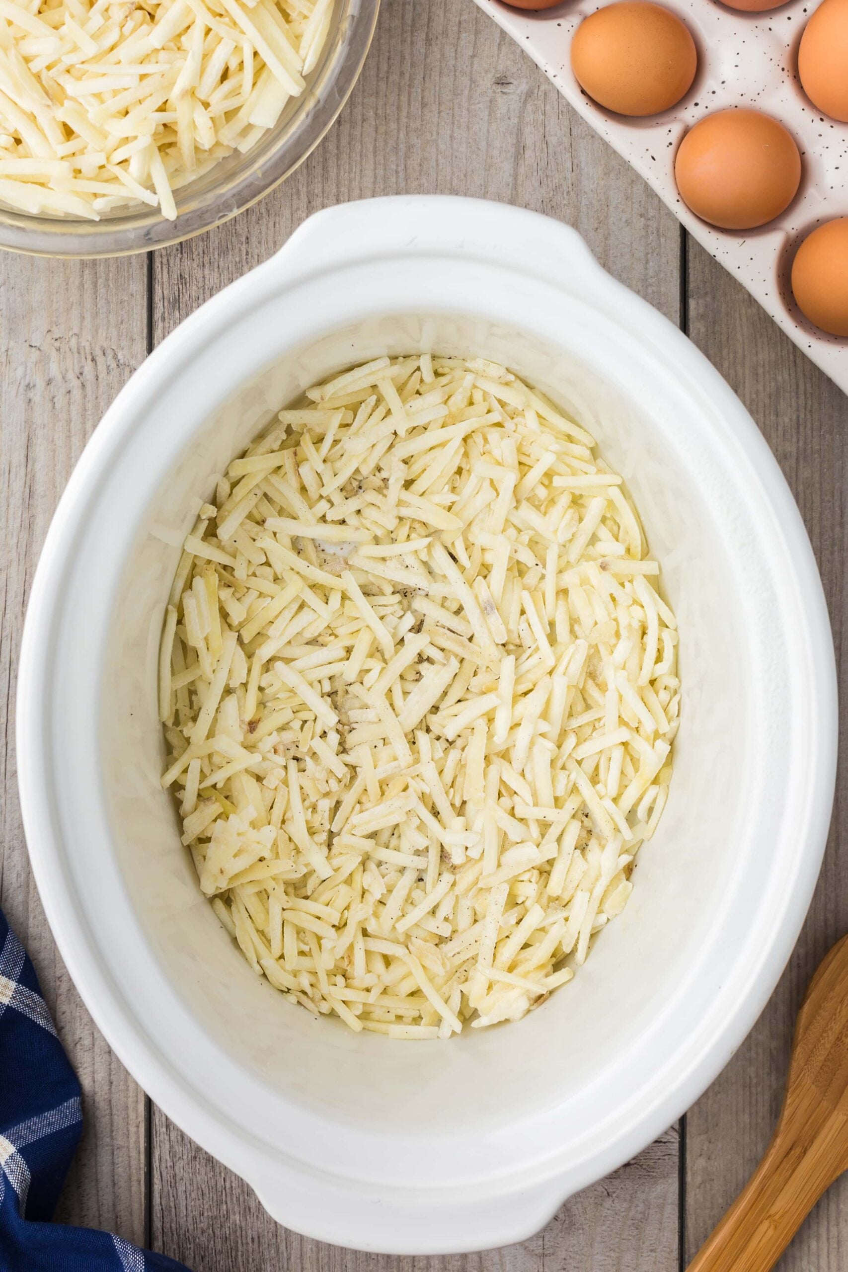 Hash browns spread in the bottom of a crockpot with salt and pepper for crock pot breakfast casserole