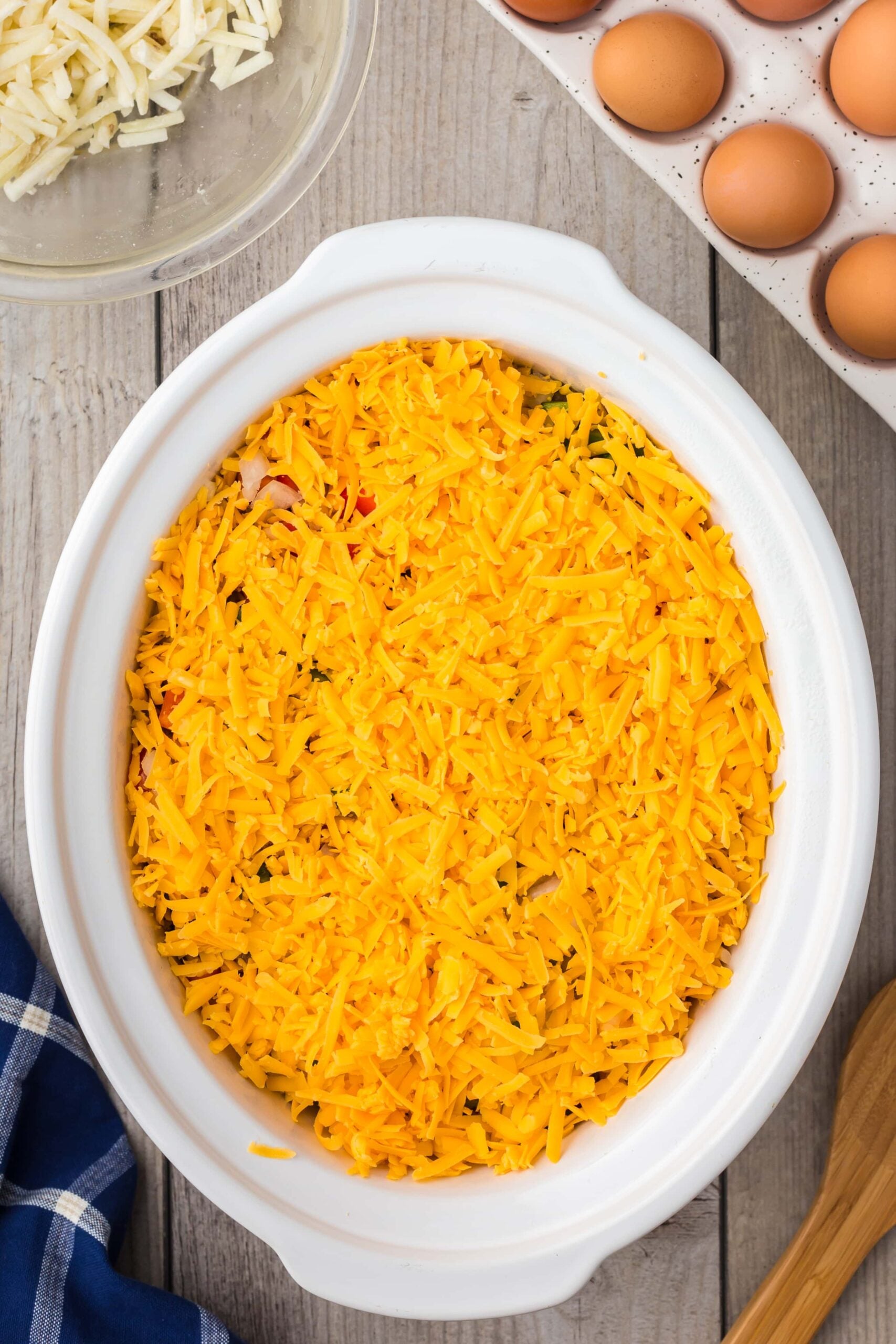 Cheese in a crock pot on top of the other layered ingredients for crock pot breakfast casserole