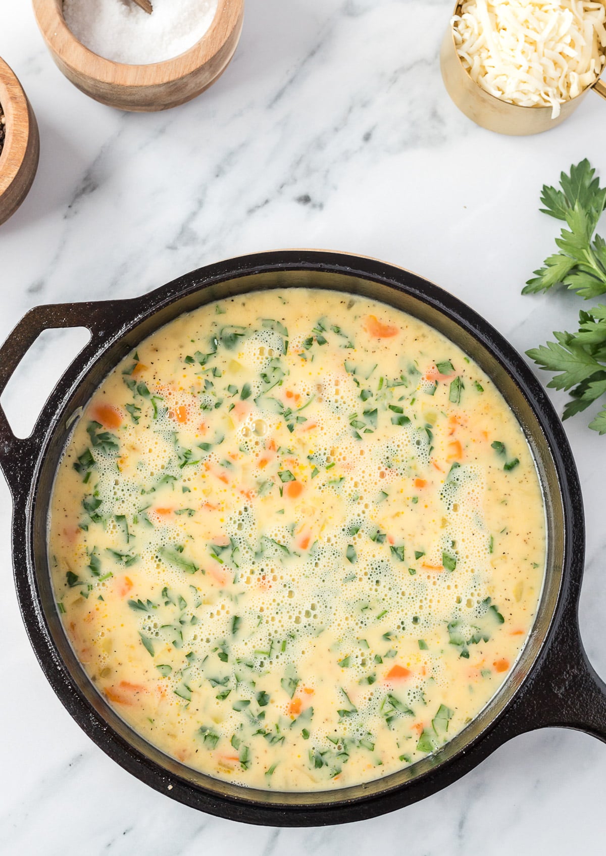 veggies and egg mixture in a cast iron skillet before being cooked for vegetable frittata