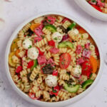 An overhead shot of healthy pasta salad in a white bowl on a grey background