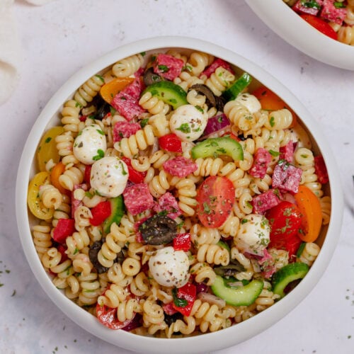 An overhead shot of healthy pasta salad in a white bowl on a grey background