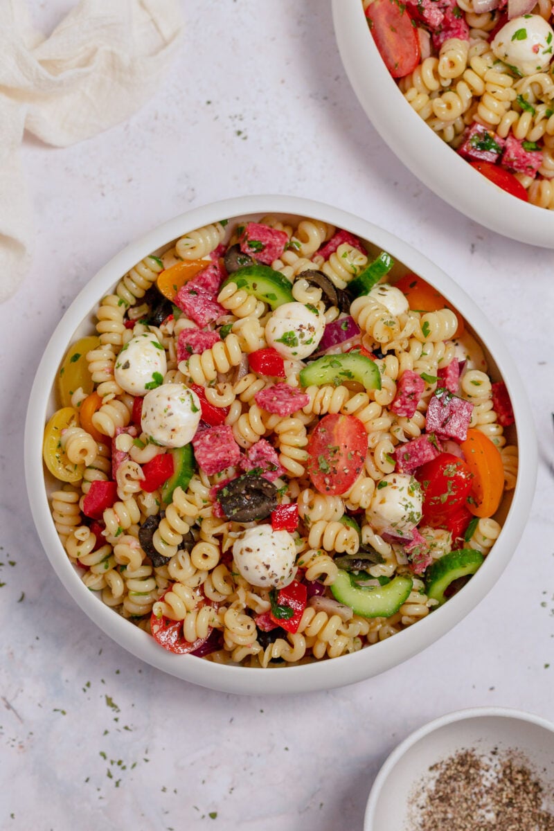 An overhead shot of healthy pasta salad in a white bowl on a grey background