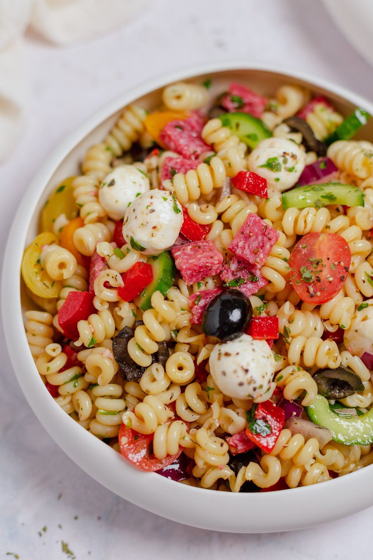 A white bowl full of healthy pasta salad on a grey background