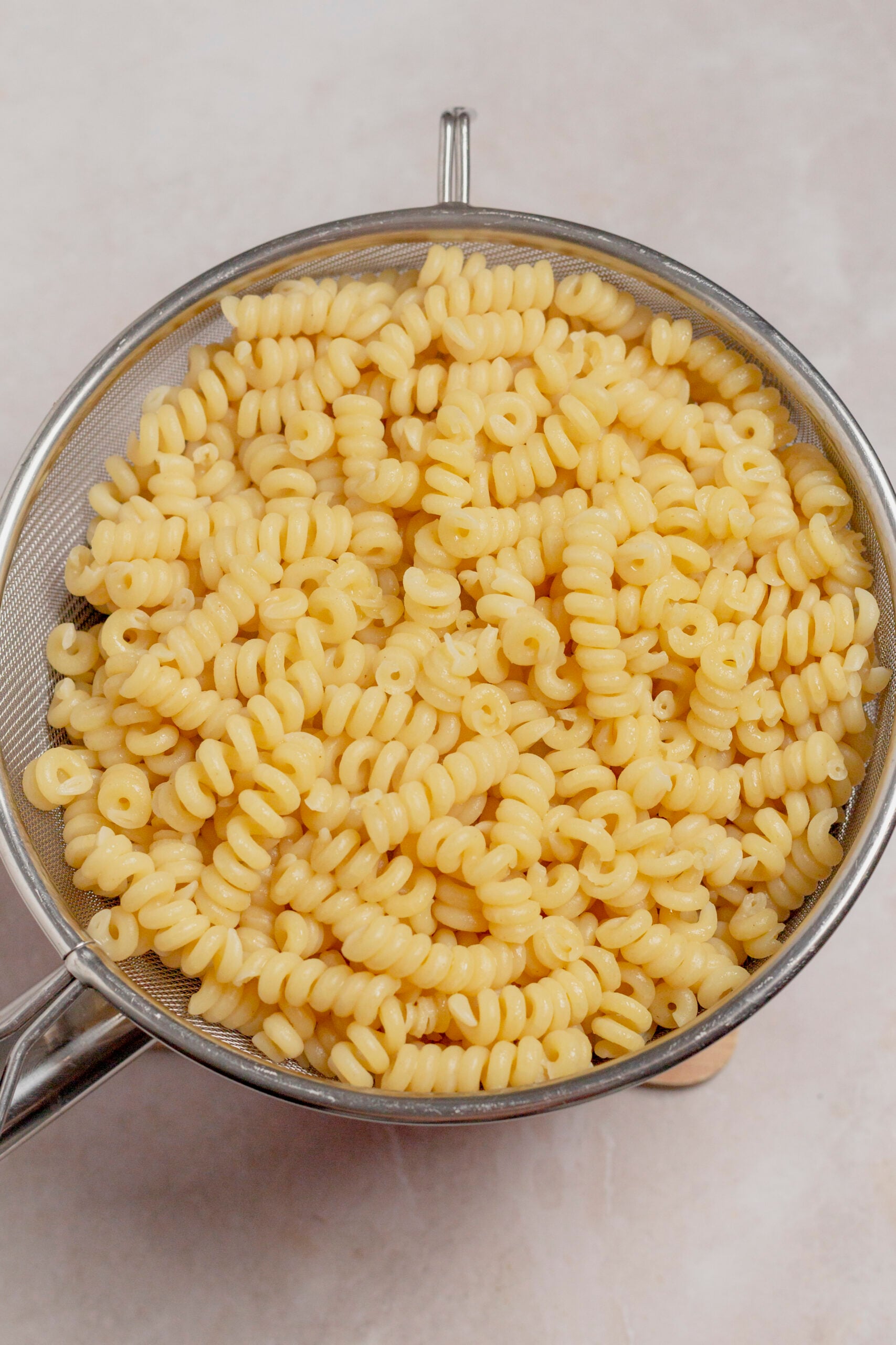 Cooked fusilli in a strainer, viewed from overhead.