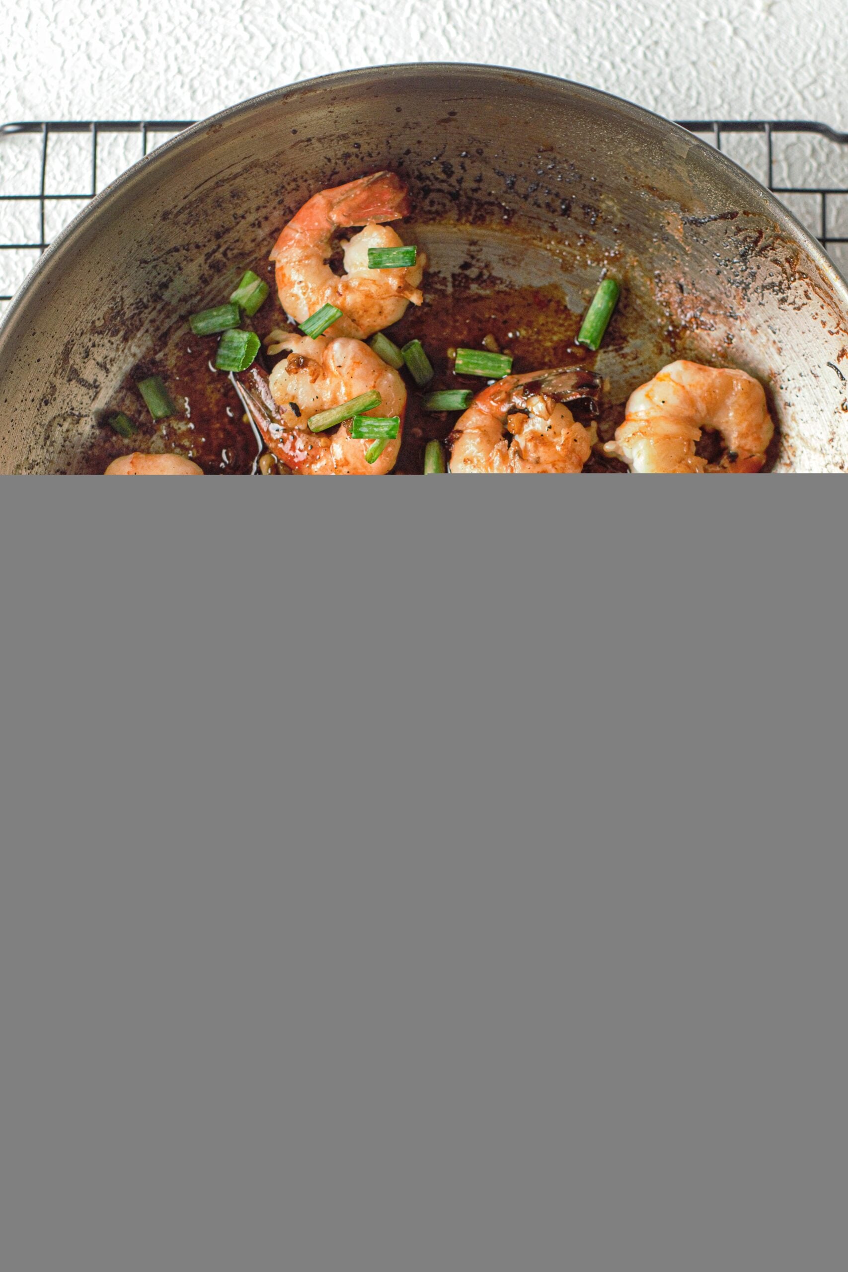 an overhead shot of honey garlic shrimp in a pan with scallions