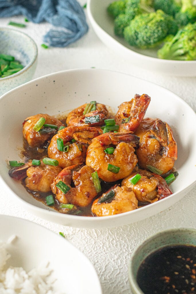 A white bowl of Honey Garlic Shrimp with scallions on top