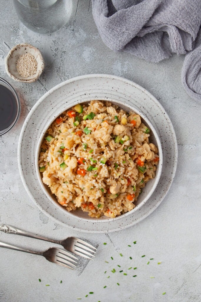 An overhead shot of a bowl of instant pot fried rice with a small bowl of sesame seeds and soy sauce and forks on the side