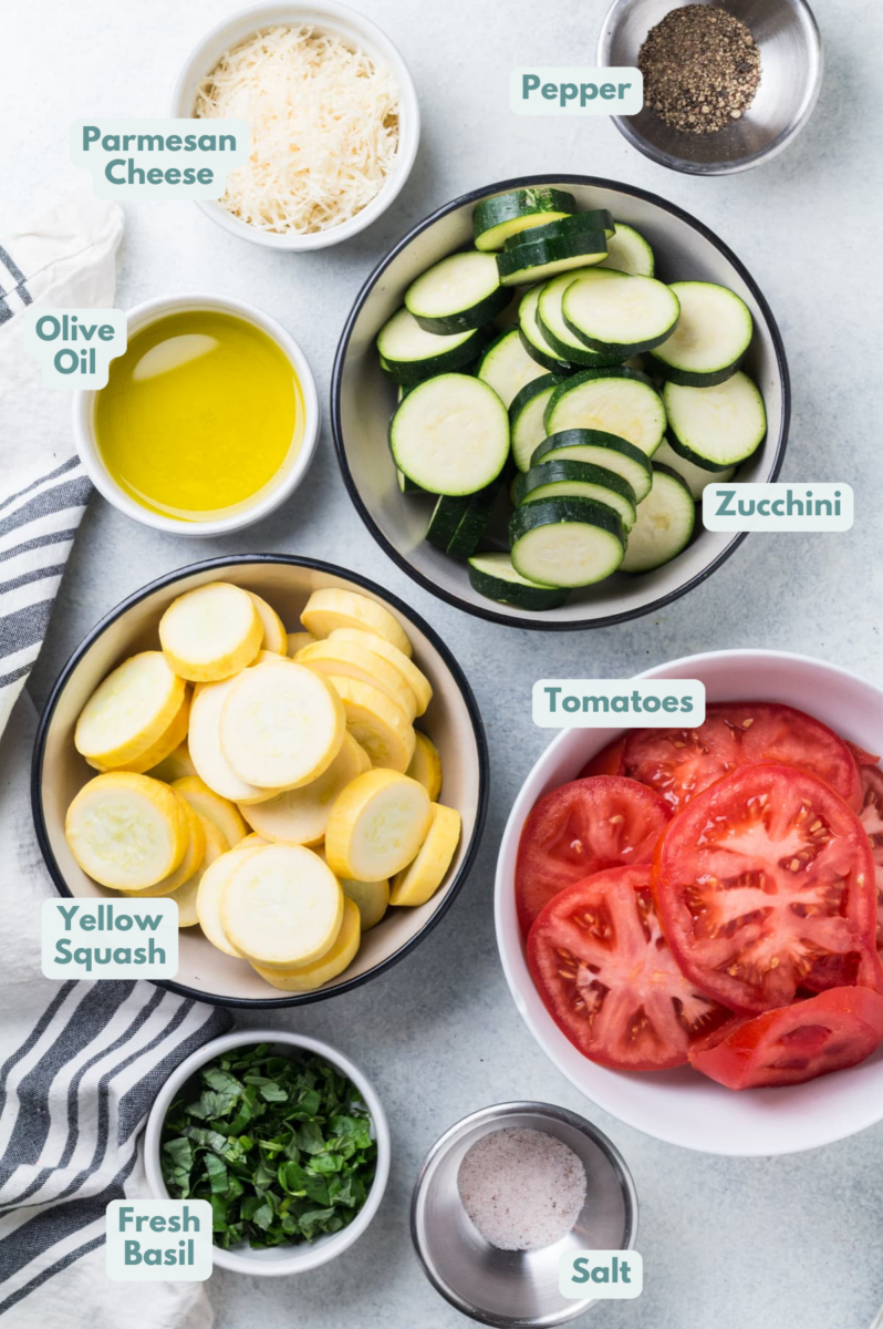 Ingredients of Zucchini Tomato Bake Casserole in small white bowls on a grey background
