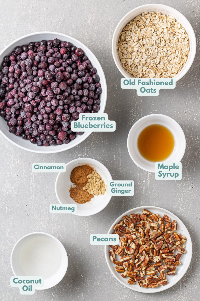 Ingredients for healthy Blueberry Crispy in small white bowls on a grey background