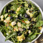 A close up of blueberry feta salad in a white bowl on a grey background