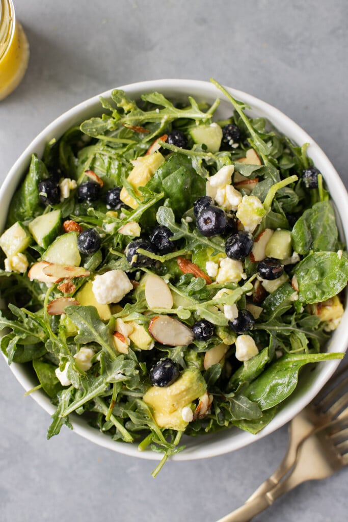 A close up of blueberry spinach salad on a grey background