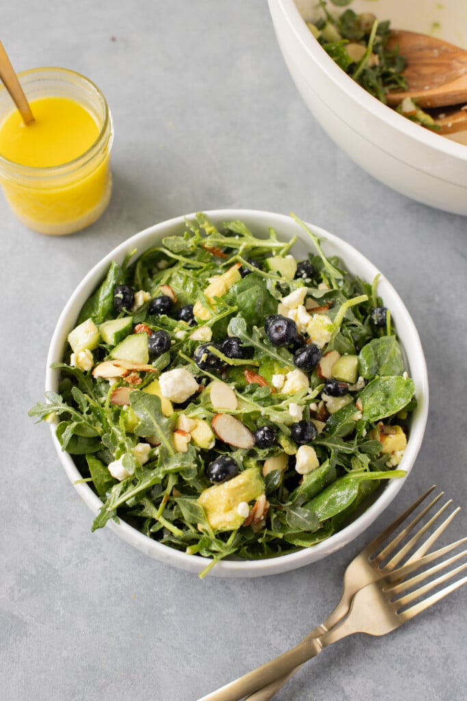 Blueberry Salad in a white bowl with citrus dressing on the side.