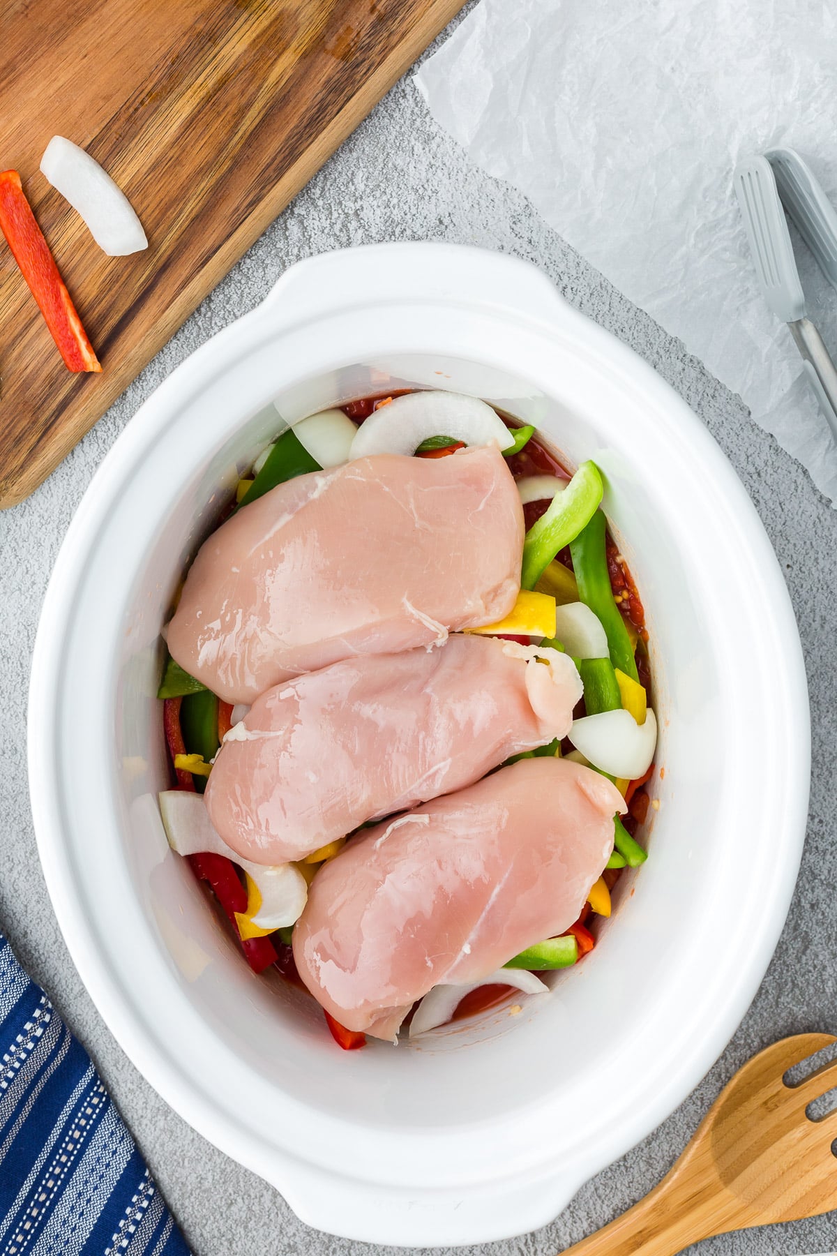 chicken breasts on top of peppers, onions, and rotel mixture for crockpot chicken fajitas