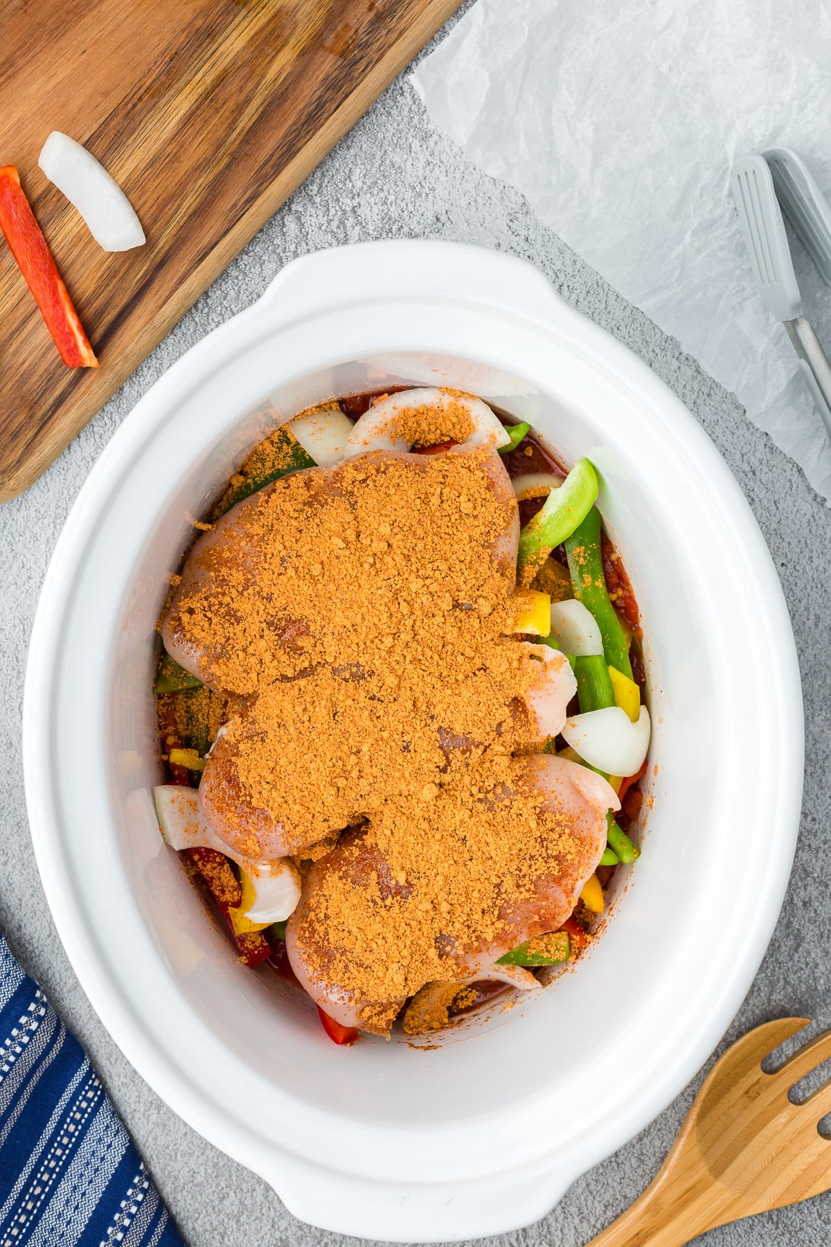 taco seasoning sprinkled on chicken in a crock pot for slow cooker chicken fajitas