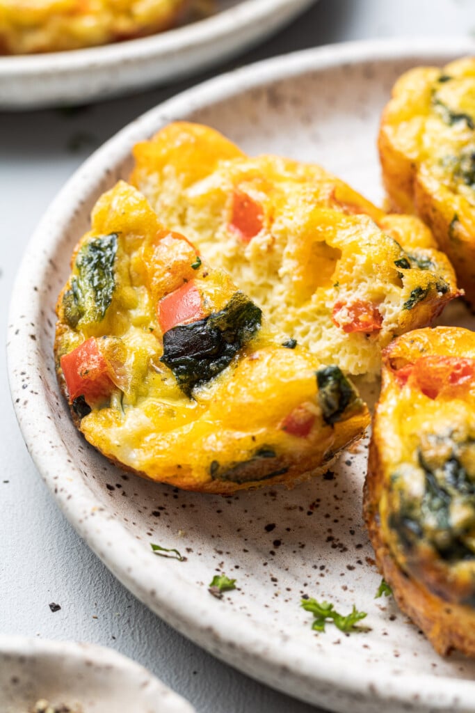 A close up of a spinach egg muffin cup with spinach and bell peppers