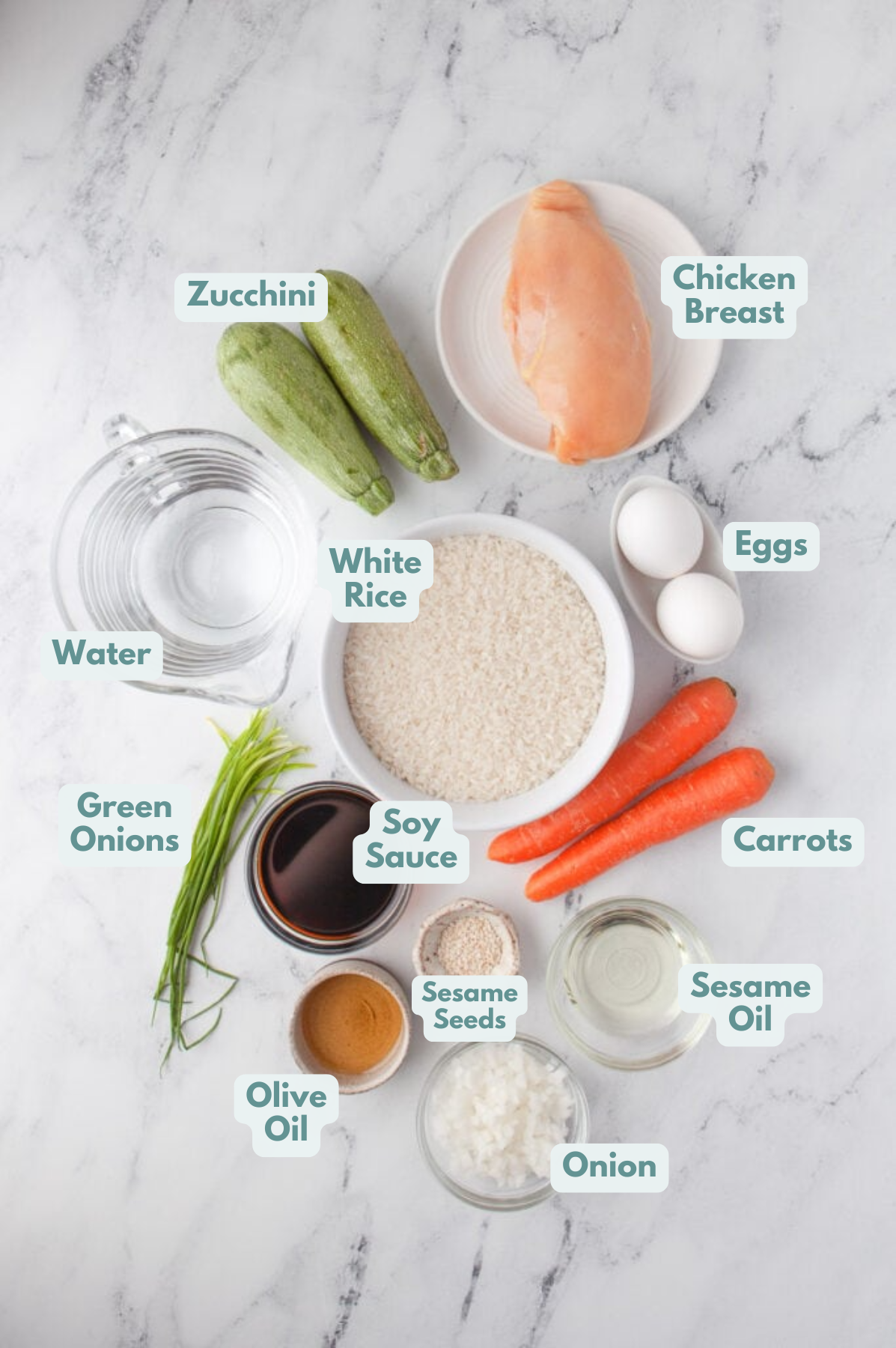 Ingredients for instant pot fried rice in white bowls on a grey background: white rice, water, olive oil, onion, carrots, zucchini, chicken breasts, eggs, soy sauce, toasted sesame oil, green onions, sesame seeds (optional)