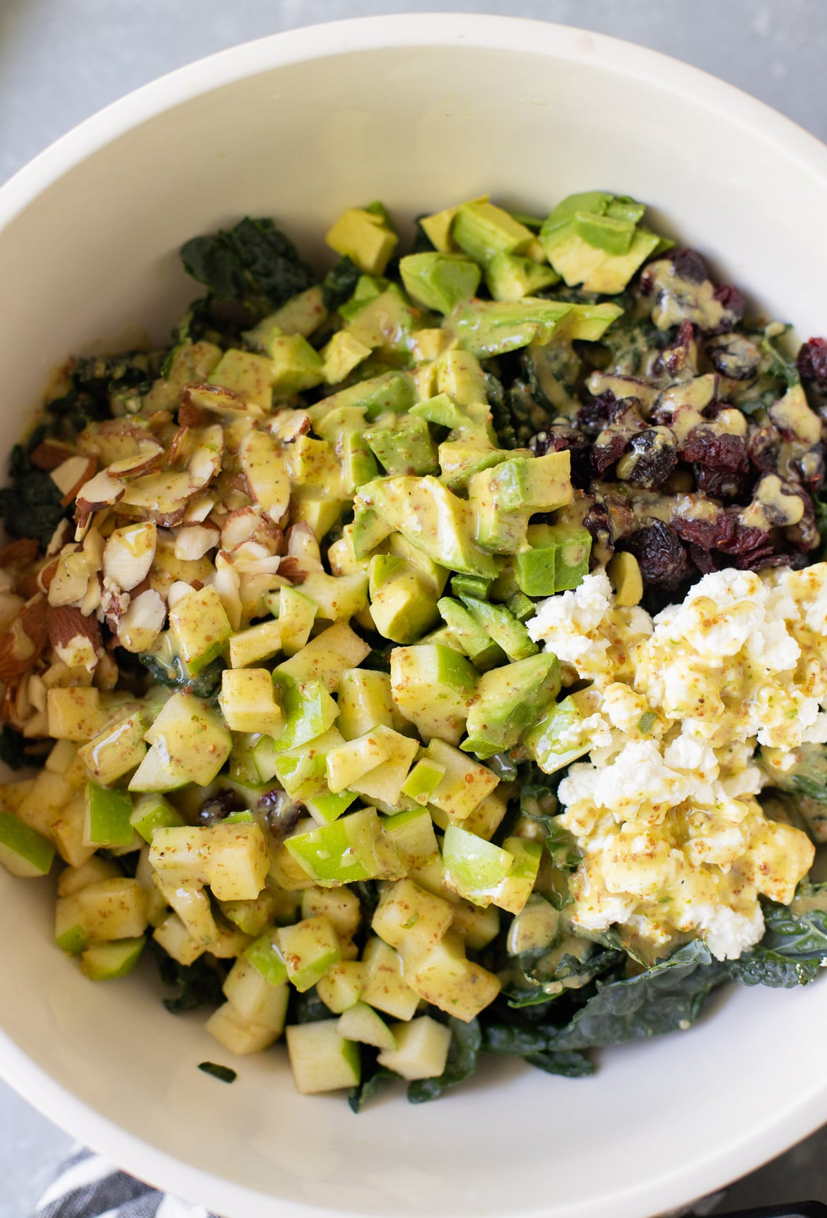 a close up of kale salad with apples, cranberries and avocados