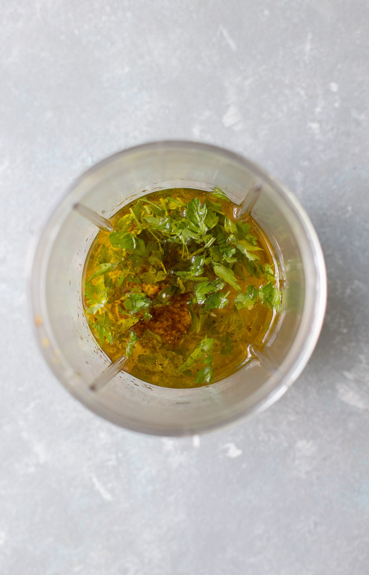 A blender filled with the ingredients of lemon mustard dressing and olive oil before being blended