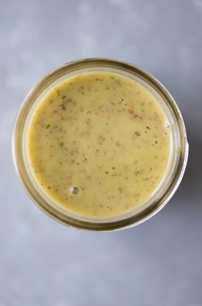 A close up of lemon mustard dressing in a glass jar