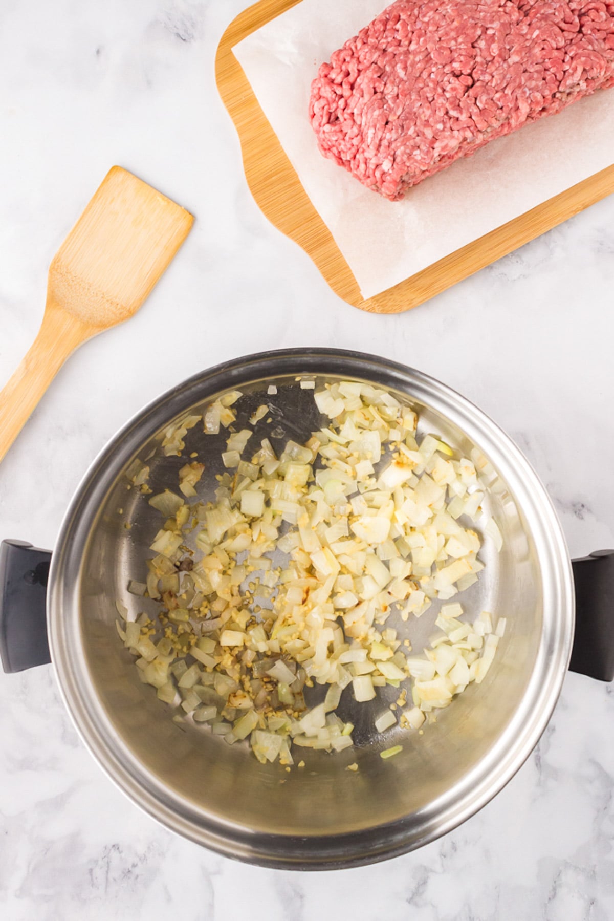 Onions and garlic after sauteing in a pot with ground beef on the side for pumpkin chili