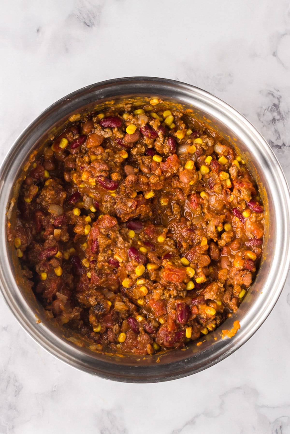 An overhead shot of a pot of pumpkin chili on a marble background