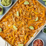An overhead image of sheet pan shrimp fajitas on a grey background