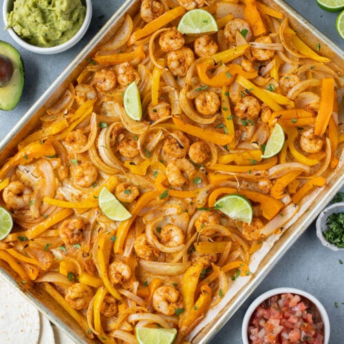 An overhead image of sheet pan shrimp fajitas on a grey background