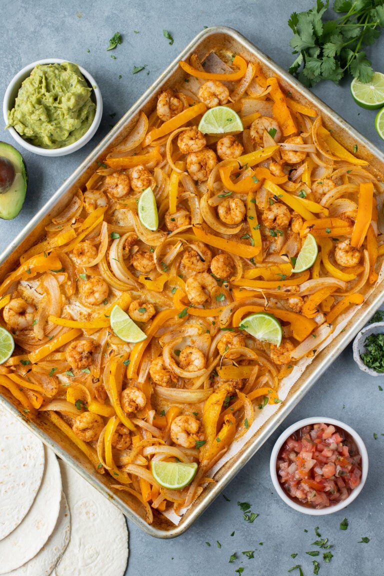 An overhead image of sheet pan shrimp fajitas on a grey background