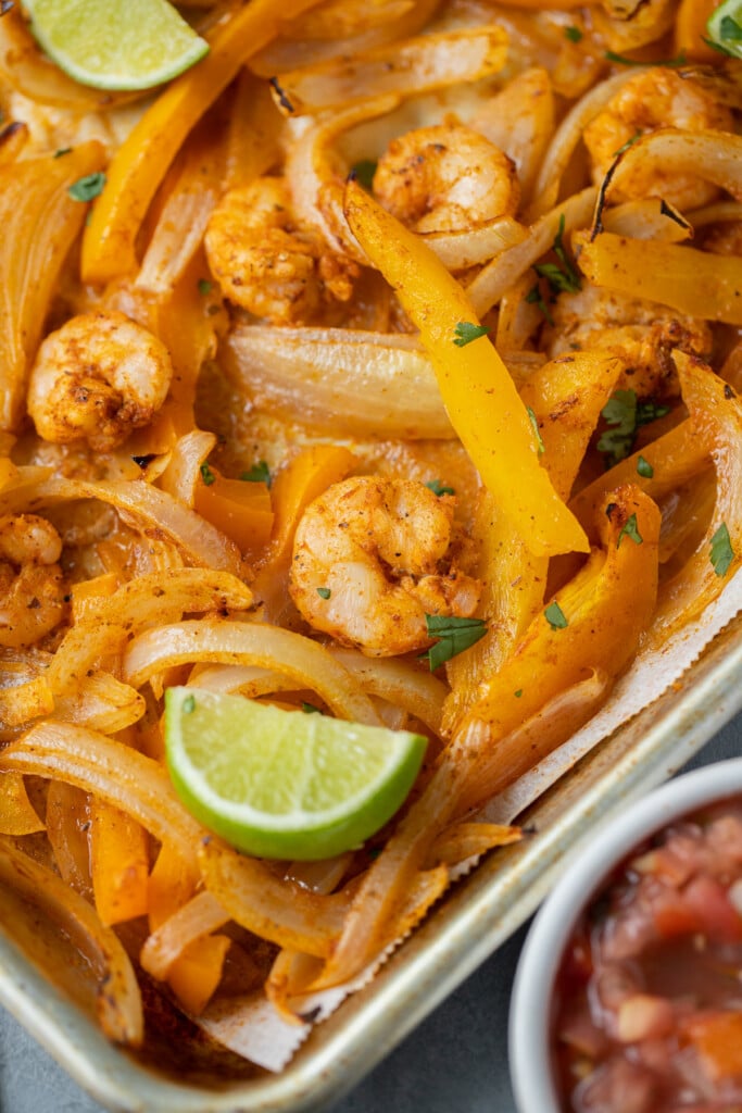 A close up of shrimp fajitas on a sheet pan