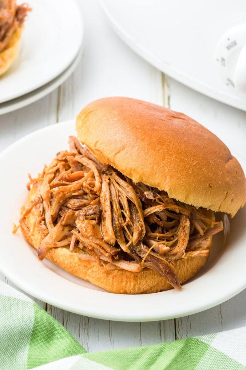 slow cooker pulled pork sandwich on a white plate on a white background