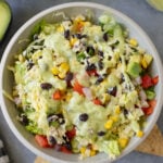 A close up of avocado ranch salad in a white bowl on a grey background