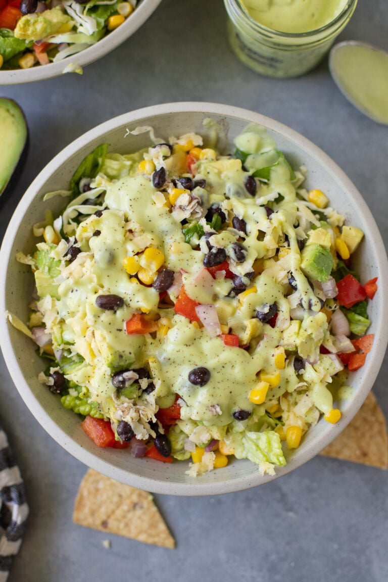 A close up of avocado ranch salad in a white bowl on a grey background