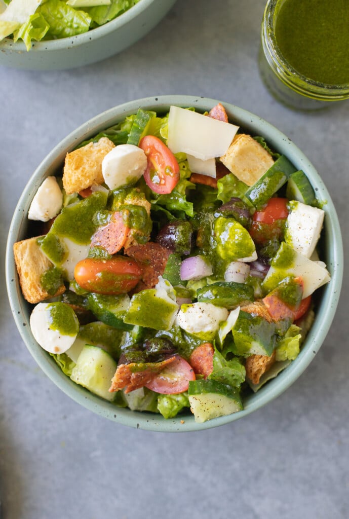 Basil Vinaigrette on top of an italian salad in a green bowl