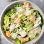 A bowl of healthy caesar salad with healthy caesar dressing on top