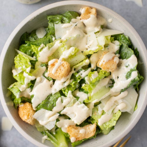 A bowl of healthy caesar salad with healthy caesar dressing on top