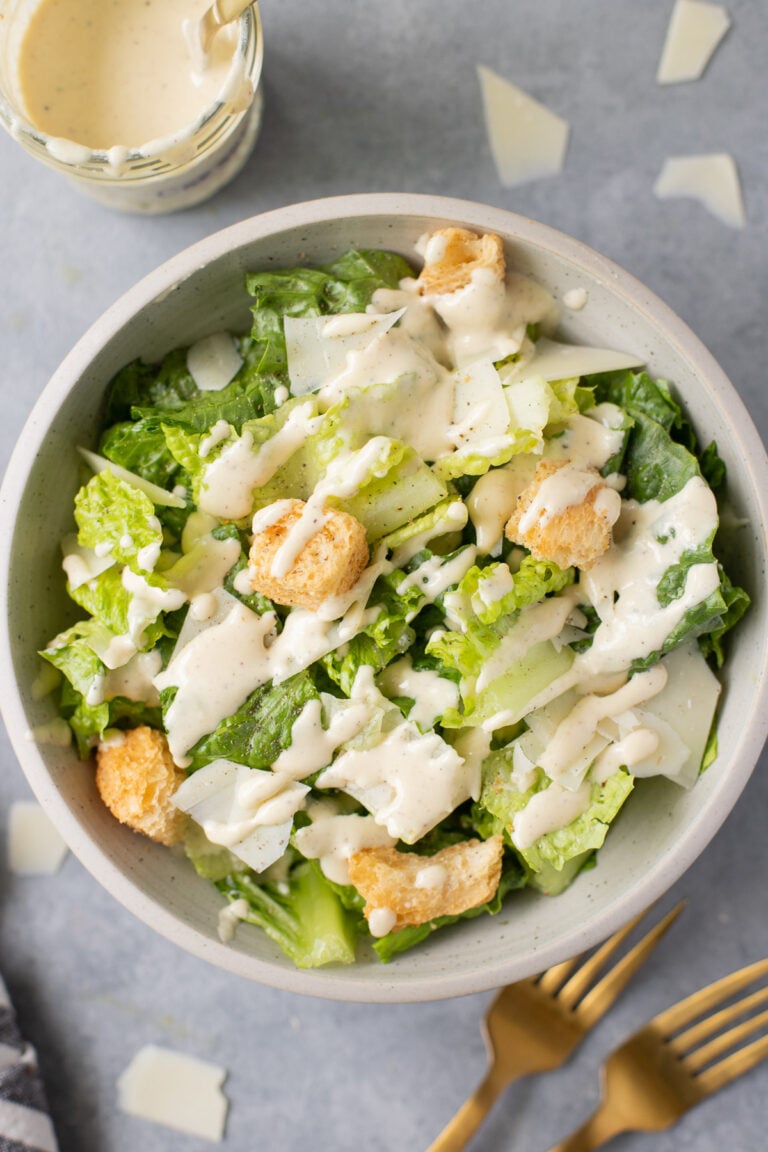 A bowl of healthy caesar salad with healthy caesar dressing on top