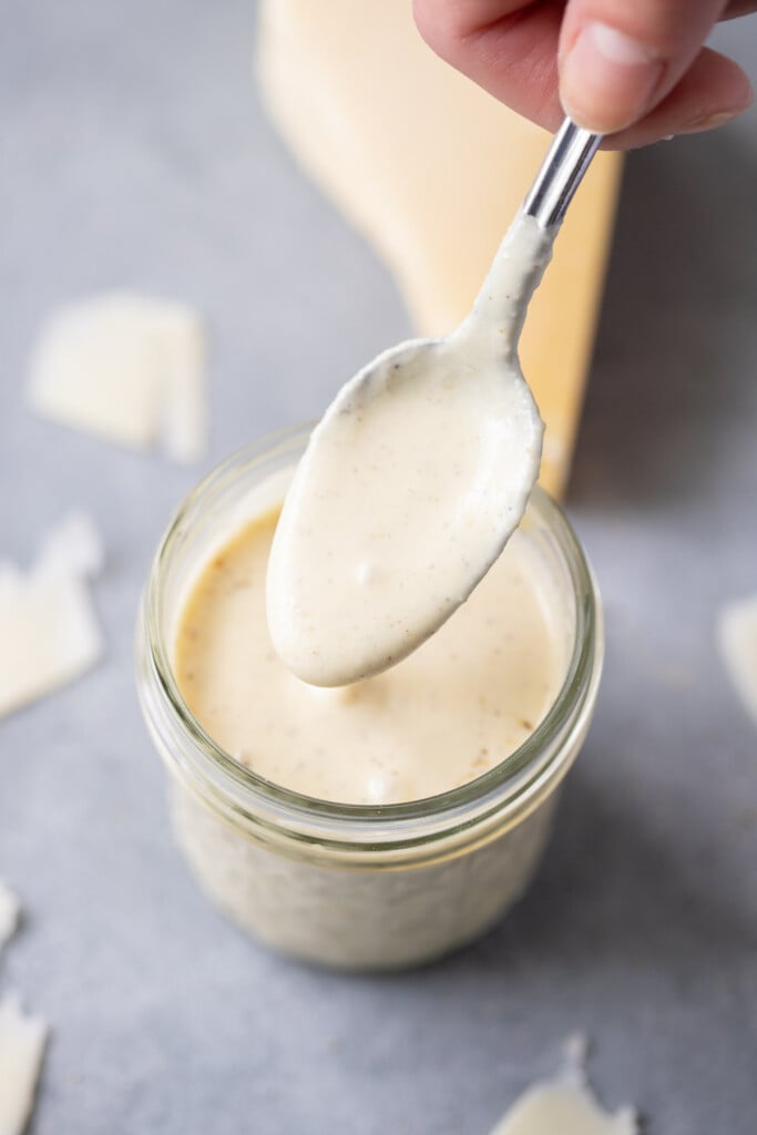 A spoon scooping into healthy caesar salad dressing