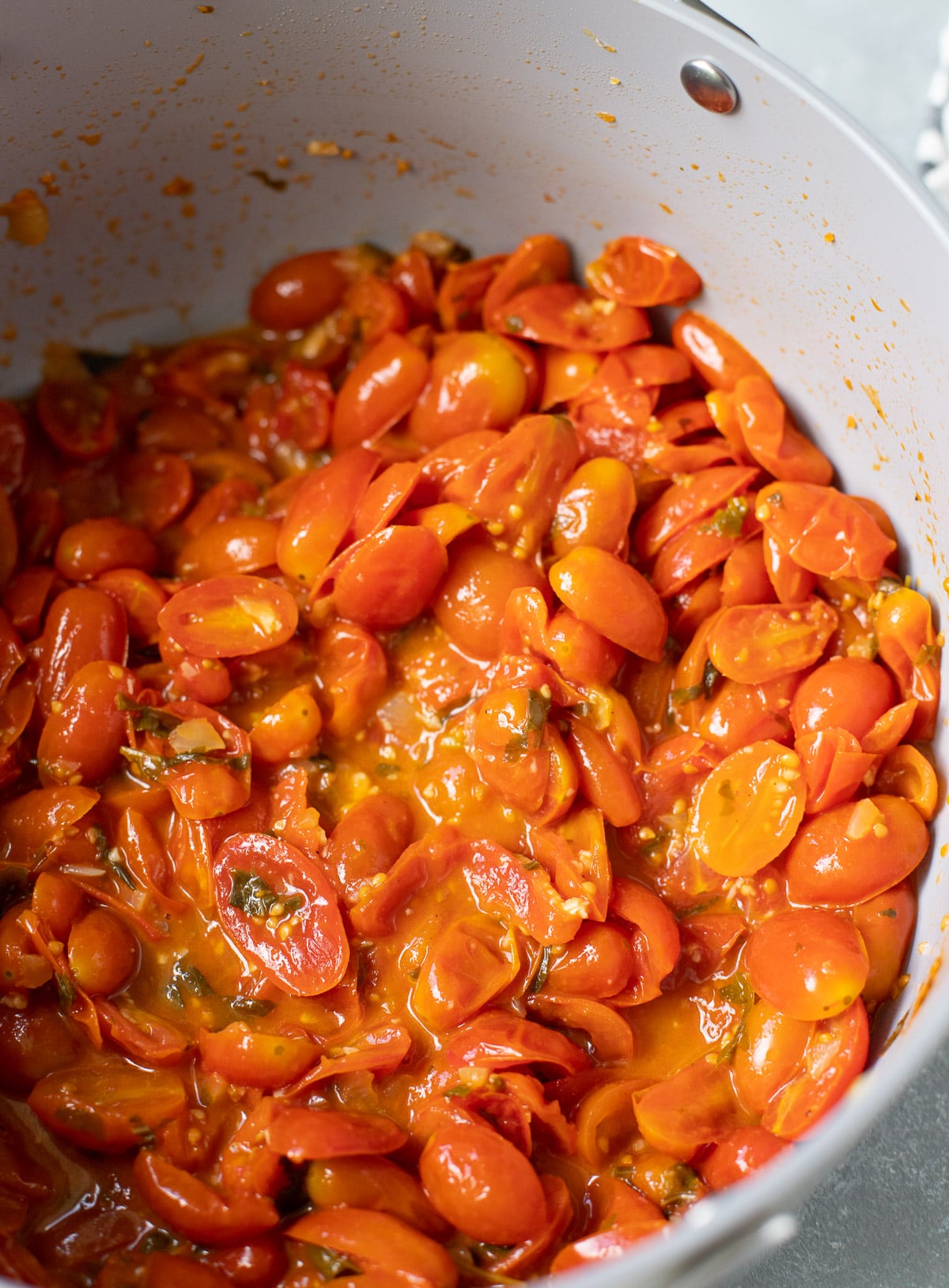 A pot of cherry tomato pasta sauce with fresh tomatoes burst open