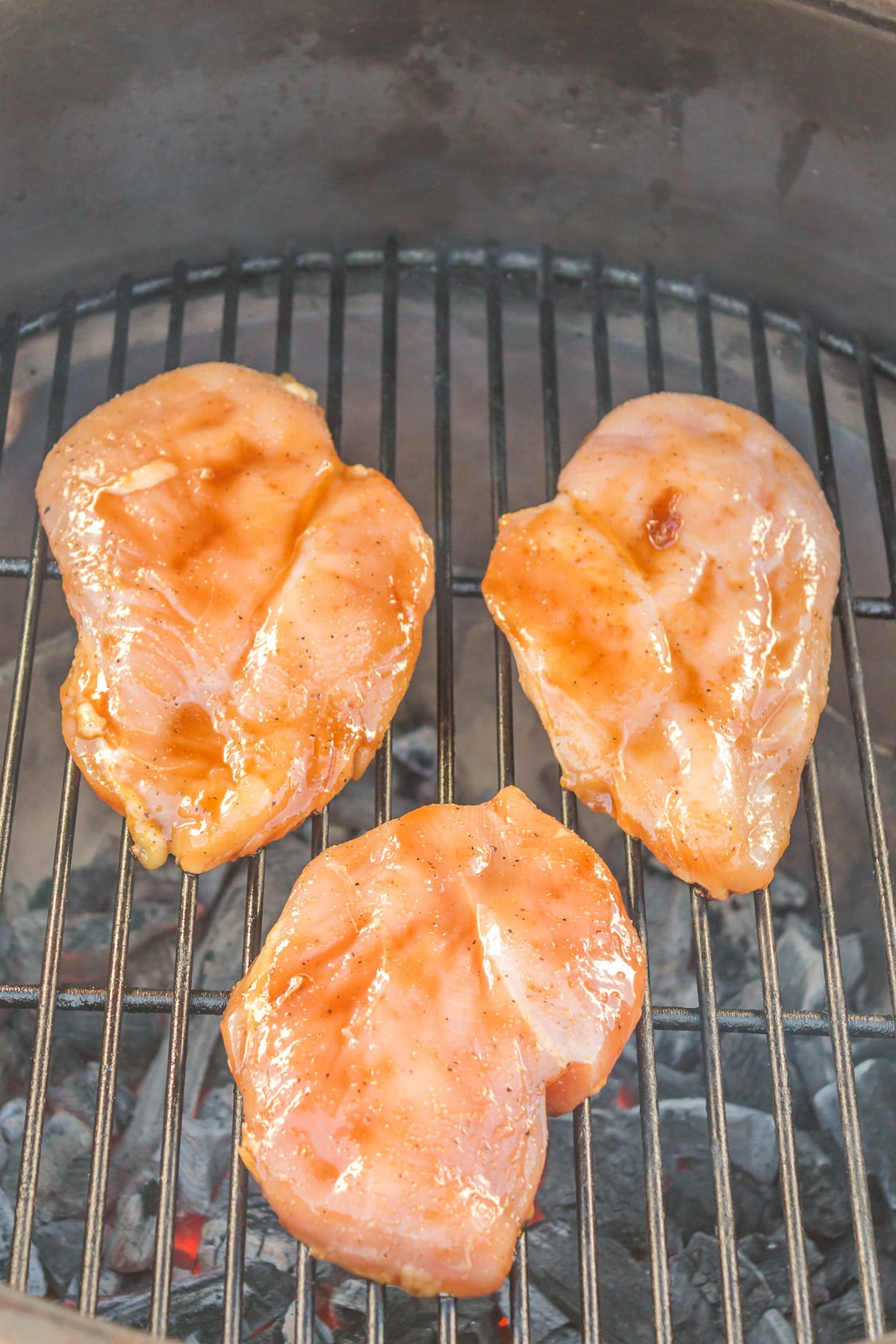 three raw teriyaki chicken breast on a grill 