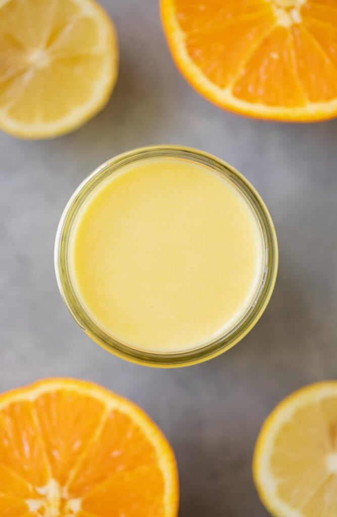 An overhead image of citrus salad dressing on a grey background with oranges off to the side