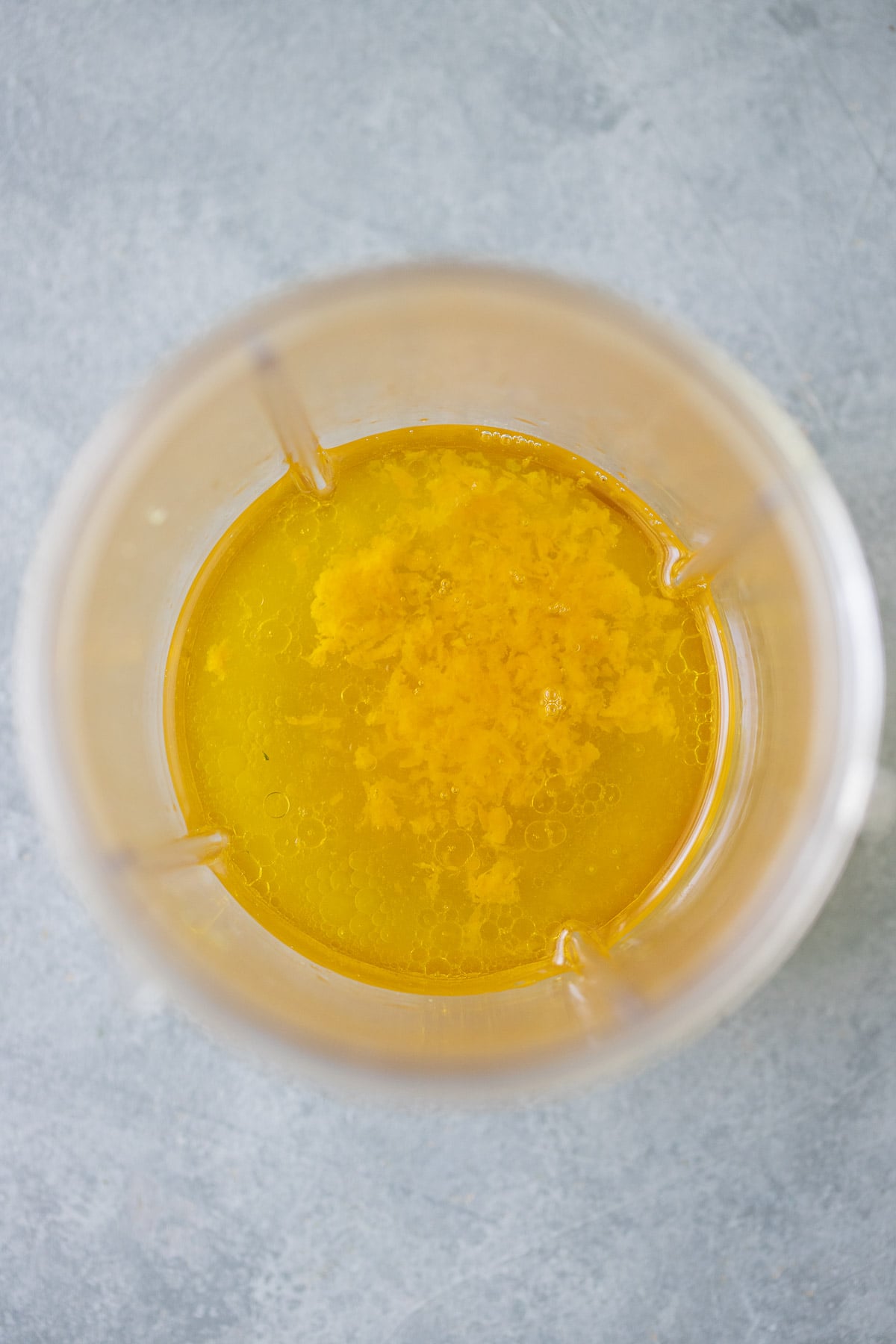 A close up of citrus salad dressing in a blender before being mixed together