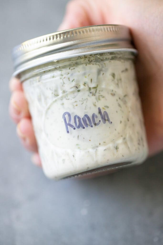 A hand holding a bottle of healthy ranch dressing